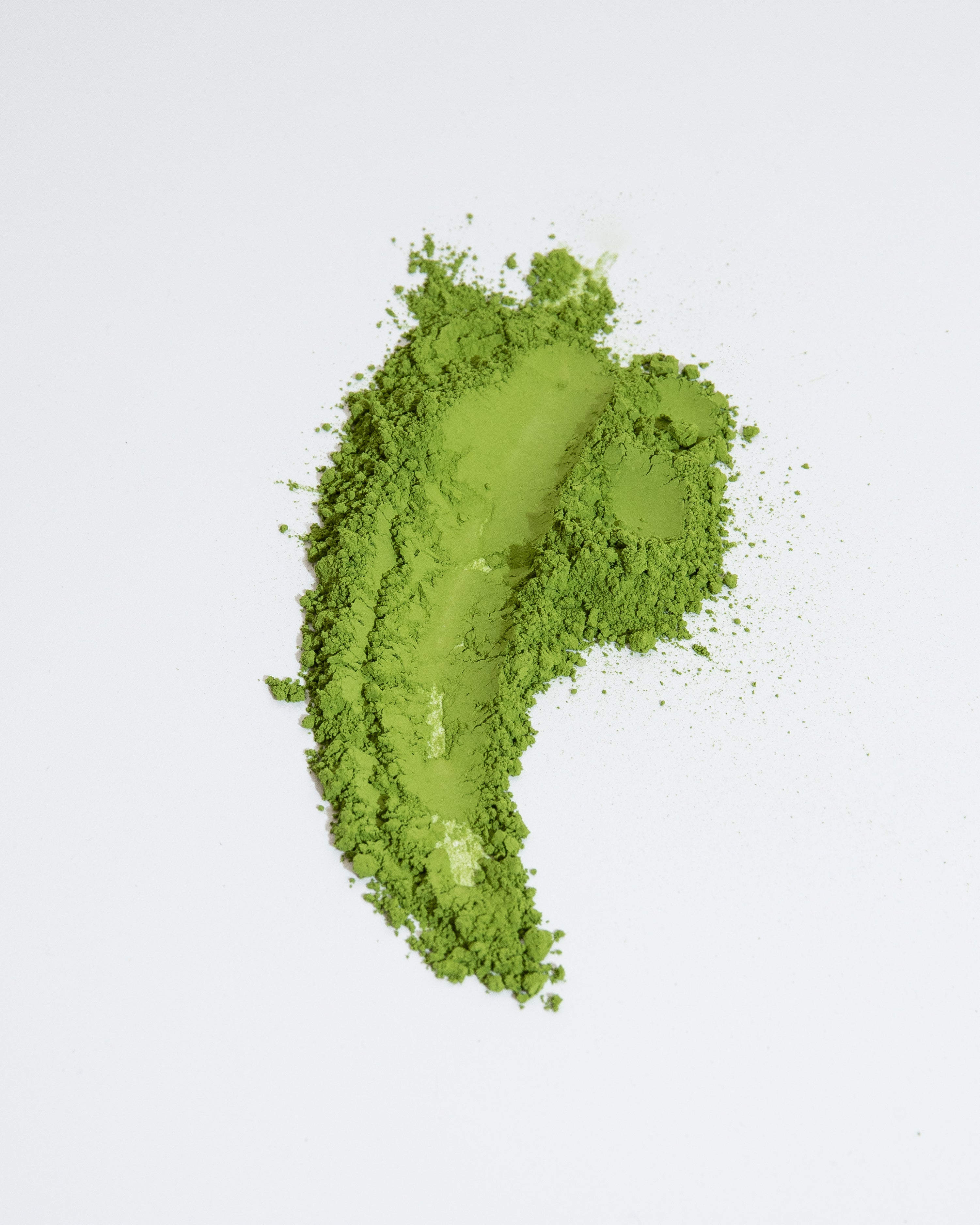 Green powder in the shape of a question mark on a light gray background